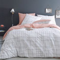 a bed with white and pink comforters in a gray room next to a lamp