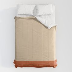 a bed with two pillows on top of it and an orange pillow under the covers