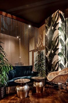 a living room filled with lots of furniture next to tall plants and wooden slats