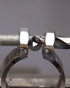 a pair of metal scissors on top of a piece of wood next to a nut and bolt