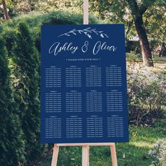 a blue wedding seating sign with mountains in the background and greenery around it on a wooden easel