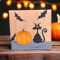 a wooden block decorated with black cats and pumpkins