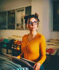 a woman wearing glasses standing in front of records