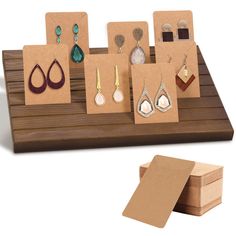 several different types of earrings are displayed on a wooden display stand with cards and magnets