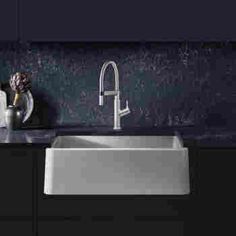 a white sink sitting under a faucet next to a counter top with flowers on it