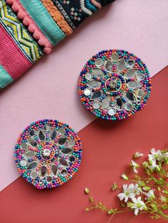 two decorative objects are sitting on a pink and red surface with white flowers in the foreground