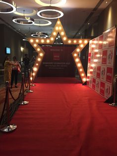 a red carpeted hallway with lights and stars on the wall, along with people standing in line