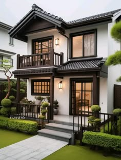 a white and black house with lots of plants on the front yard, stairs leading up to it