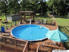 an above ground pool surrounded by decking and umbrellas