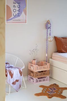 a room with a bed, table and chair in it next to a poster on the wall