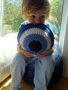 a young boy holding a crocheted blue and white object