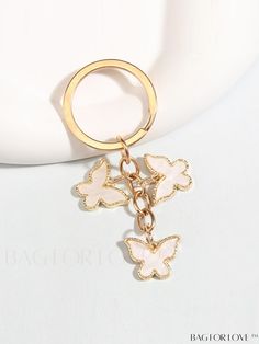 a gold keychain with butterflies attached to it's chain on top of a white surface