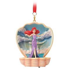 the little mermaid ornament is hanging from a red ribbon