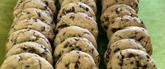 chocolate chip cookies are arranged in rows on a green tablecloth, ready to be eaten