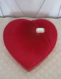 a red heart shaped pillow sitting on top of a bed