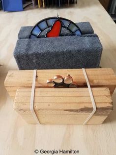 two rings sitting on top of a piece of wood next to a stained glass window