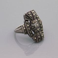 an antique silver ring with filigrees on it's sides, sitting on a gray surface