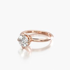 a rose gold engagement ring with a round diamond in the center, on a white background