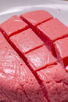 four pieces of pink cake sitting on top of a white plate with red icing