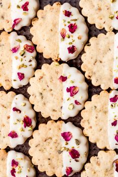 several cookies with white frosting and pink flowers on them are lined up in rows