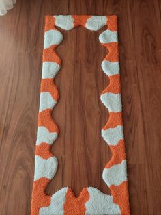 an orange and white rug on the floor in front of a wood flooring area