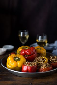 some red and yellow bell peppers on a plate with wine glasses in the back ground