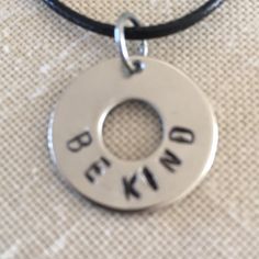 a necklace with the words be kind written on it and a circle in the middle