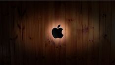 an apple logo is lit up on a wooden wall with wood grained walls behind it