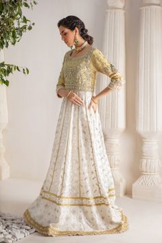 A contemporary Classic - Over a canvas of Pure chikankari chiffon, features a beautiful floral embroidered bodice further enhanced with dabka, sequins, pearls and kundan work. This classy peshwas is paired with gorgeous kamdani work dupatta, making this an absolute favorite for nikkah, engagement & other celebratory festivities Hand crafted tassels & straight pant completes the look of this outfit. Peshwas Fabric: Pure Chiffon Peshwas Length: 60” (customisable, mention in order notes) Sleeve length: 16” Pant Fabric: Khaadi Silk Dupatta Fabric: Georgette Chiffon Color: Ivory & Gold This outfit is fully lined, neck key-hole can be lined on request, mention in order notes. Please refer Size Guide Before selecting size For Customised measurements please select Custom size for an additional 20$ Designer Cream Chanderi Dress, White Georgette Dress With Mirror Work, Embroidered Dress For Wedding Diwali, Embroidered Embellished Dress For Wedding And Diwali, Intricate Embroidered Anarkali Dress In Chanderi, Raw Silk Anarkali Set With Chikankari Embroidery For Reception, Cream Anarkali Set With Dabka Work For Reception, Anarkali Embroidered Dress With Mirror Work For Weddings, Festive Choli With Chikankari Embroidery For Reception