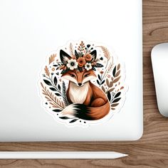 a laptop with a sticker of a fox and flowers on the screen next to a mouse