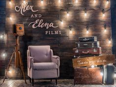 a chair sitting in front of a wooden wall with lights on it and suitcases next to it