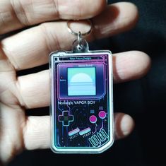 a hand holding a small gameboy keychain