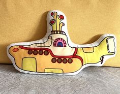 a yellow submarine shaped pillow sitting on top of a bed next to a brown wall