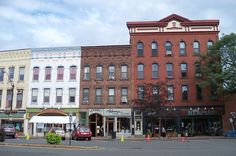 there are many buildings on the corner of this street, and one is red with white trim