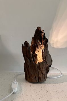 a table lamp made out of wood with a light bulb on the side and plugged in