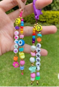 a person is holding some colorful beads in their hand with the words happy written on them