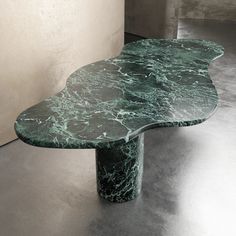 a green marble table sitting in the middle of a room next to a white wall