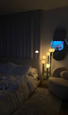 a white bed sitting next to a window in a bedroom under a blue light on the wall