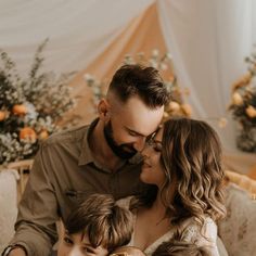 a man and woman are sitting on a couch with their two children in front of them