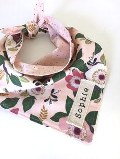 a pink scarf with flowers on it and a name tag hanging from the neckline