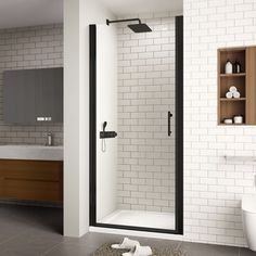 a bathroom with a white toilet and black frame shower door, along with an open shelving unit on the wall