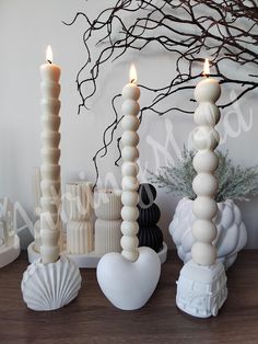 three candles sitting on top of a wooden table next to vases and other items