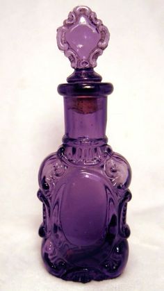 a purple glass bottle sitting on top of a white table