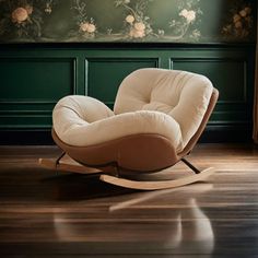 a white rocking chair sitting on top of a hard wood floor next to a green wall