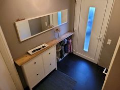 a hallway with a white door and mirror on the wall next to a black floor