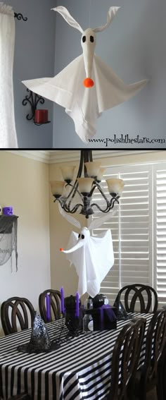 a dining room table decorated for halloween with black and white striped table cloths, ghost head hanging from the chandelier