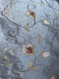 an embroidered fabric with gold and silver flowers on it's side, in the middle of