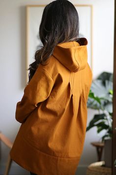 the back of a woman's yellow jacket in front of a potted plant