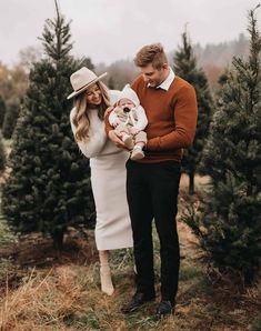 a man and woman standing in front of christmas trees