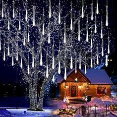 christmas lights hanging from a tree in front of a house with snow on the ground